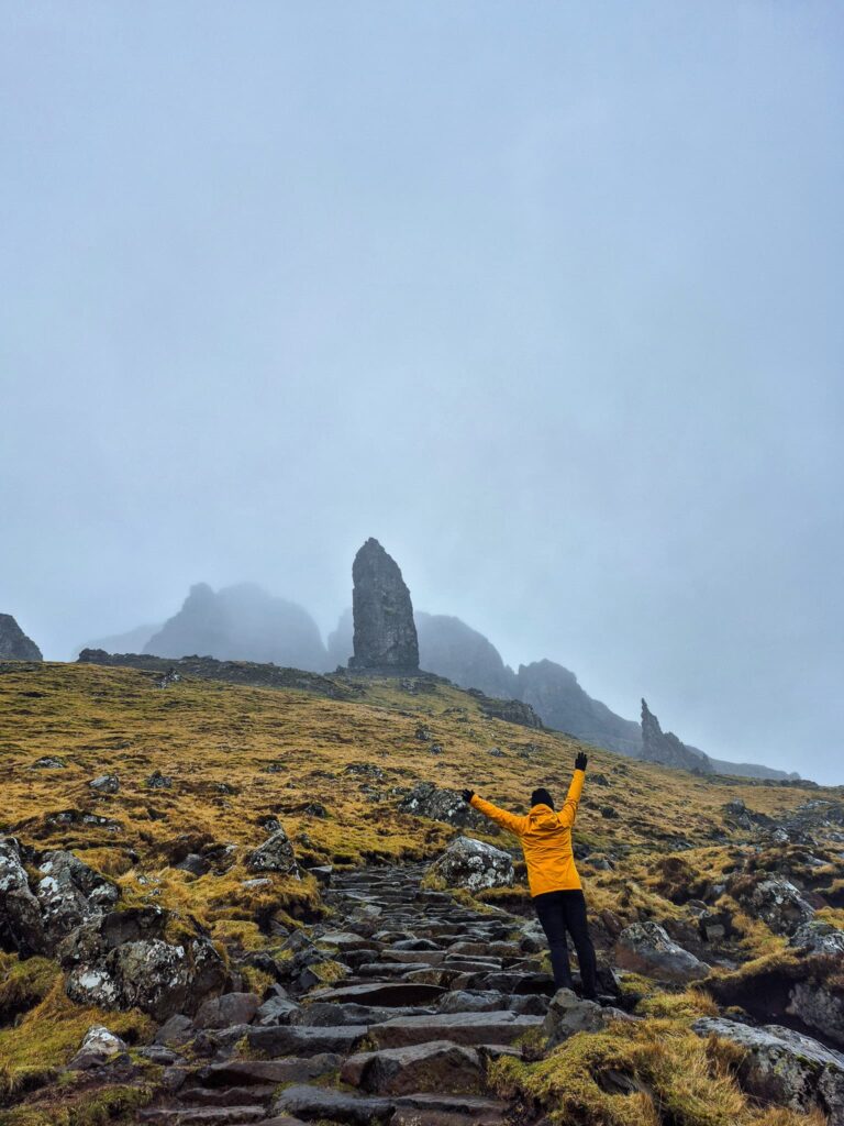Alina with her back to the camera facing the Old Man of Storr rock formation on Isle of Skye.