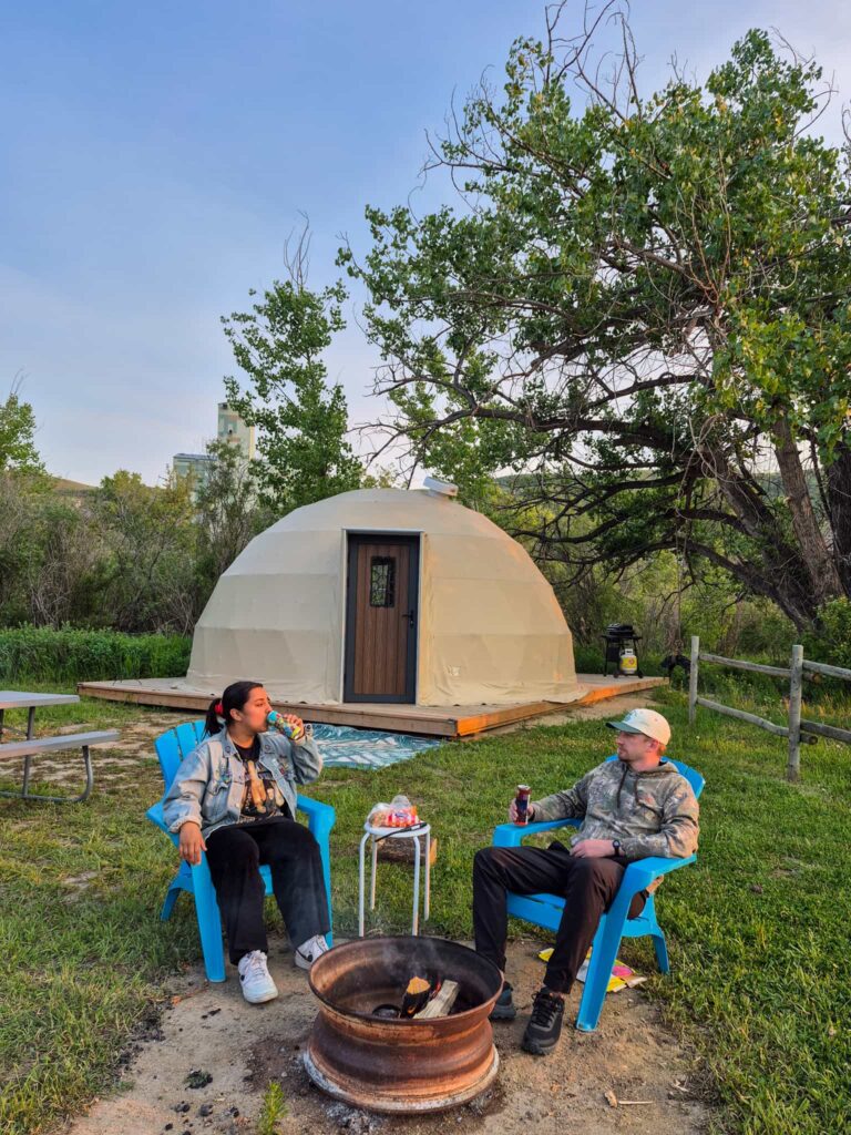 Alina and Justin enjoying snacks by the fire in front of the Rainforest Geodome.
