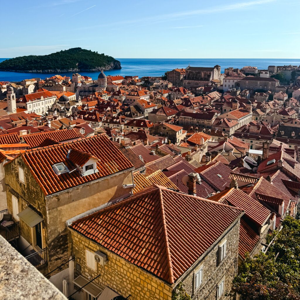 View of Old Town Dubrovnik from the City Walls. There are many terracotta roofed buildings.