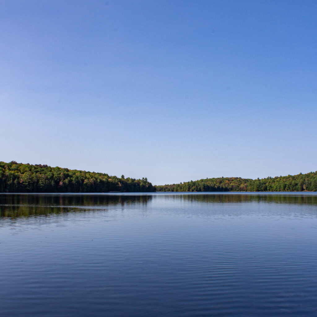 A horizon view of Silent Lake in Ontario. The lake is in the foreground and the sky in the background, while the shoreline cuts through the middle of the photo.