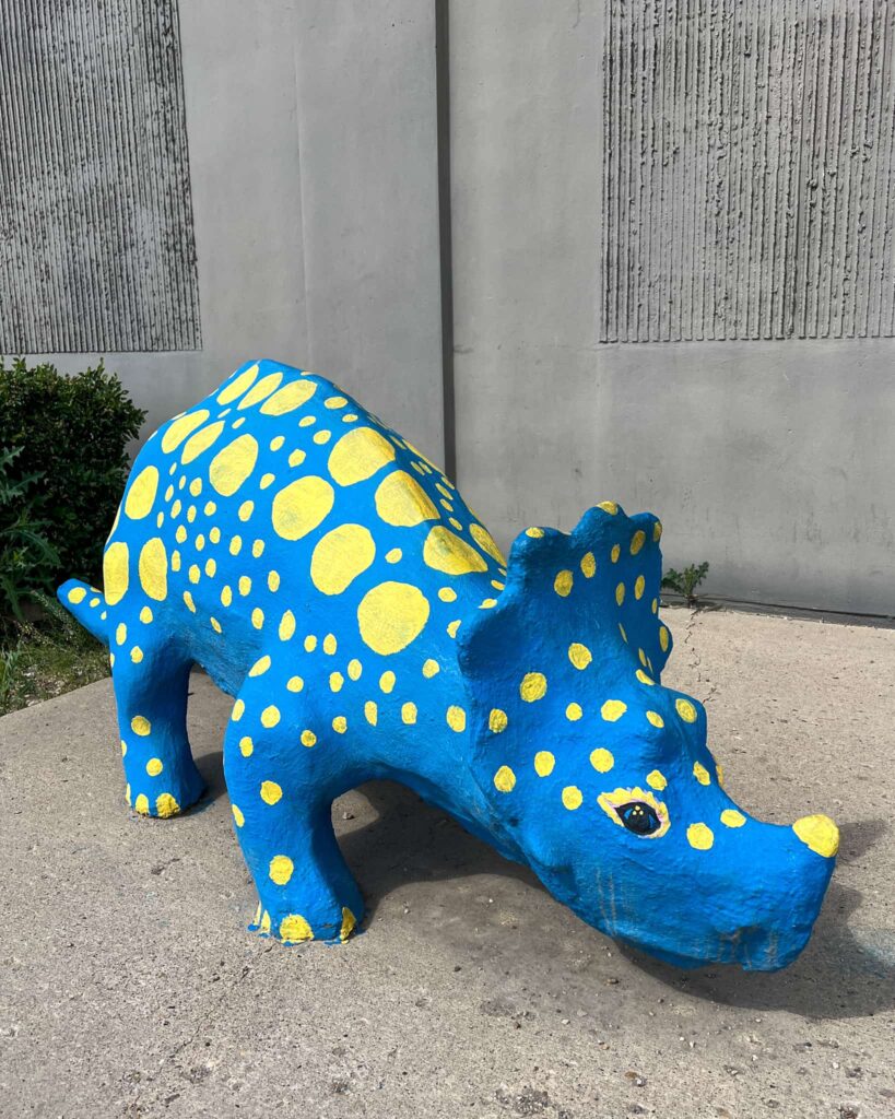 A statue of a triceratops in downtown Drumheller. It is royal blue with many yellow spots.