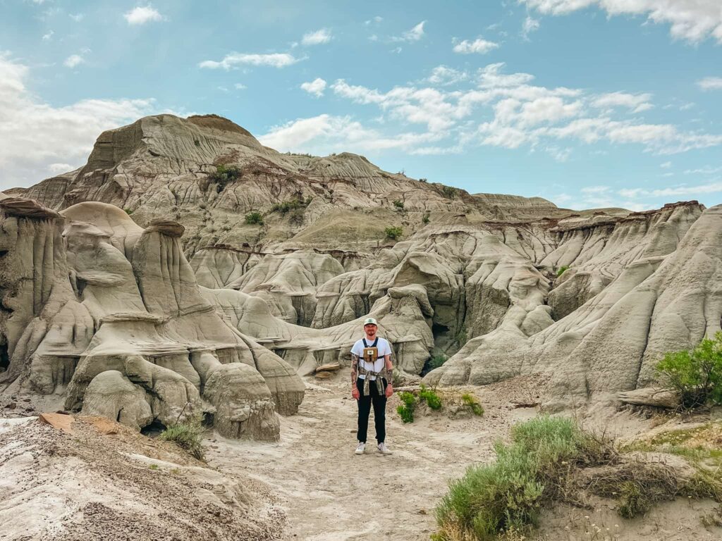 Justin standing in front of some cool geological formations in Dinosaur Provincial Park