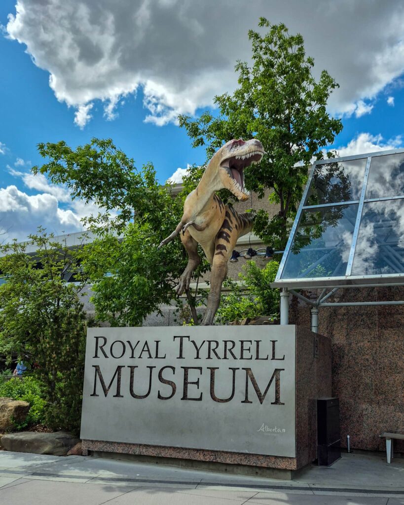 The entry sign outside the Royal Tyrrell Museum. On top there is a yellow velociraptor.