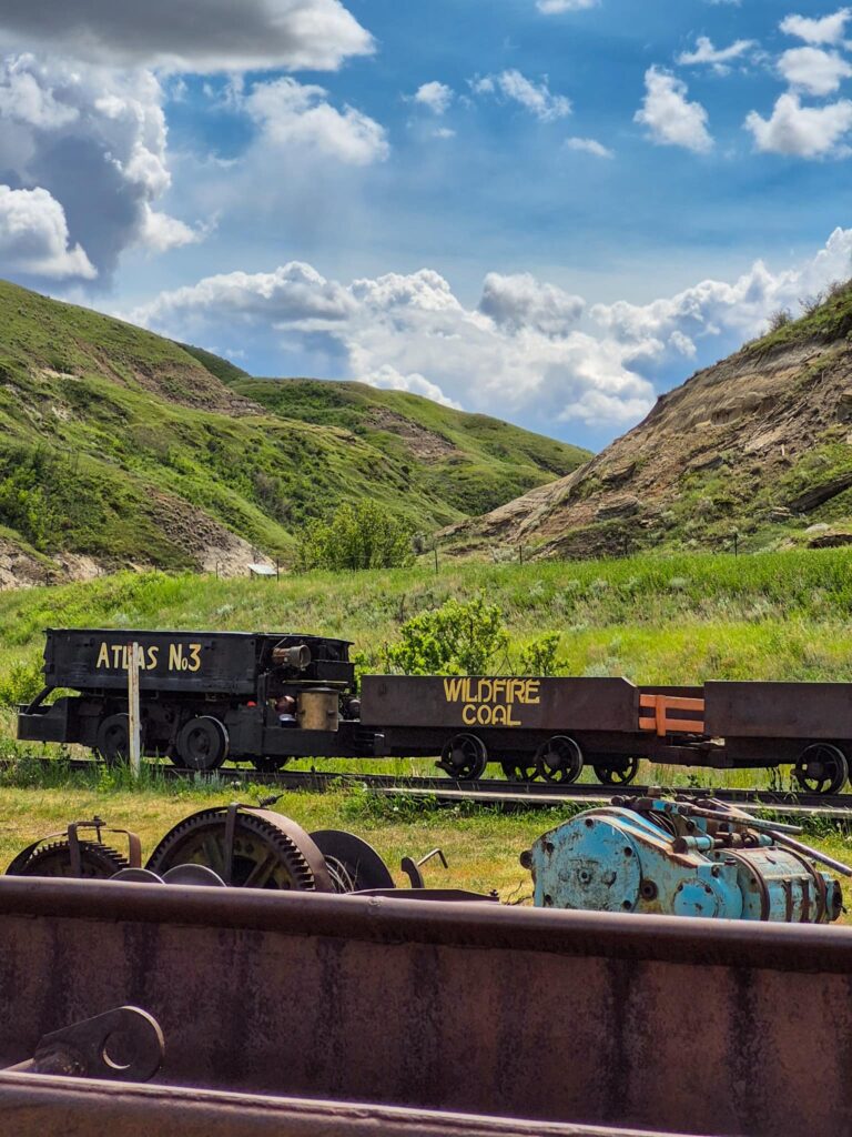 Mine Train with "Atlas No3" spray painted in yellow on locomotive. A mine cart has "Wildfire Coal" written on it.