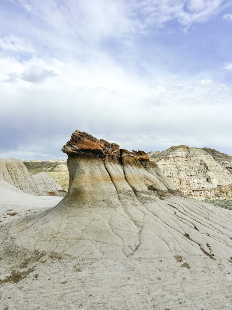 A small hoodoo that is pretty wide, with small mushroom capped rocks on top.