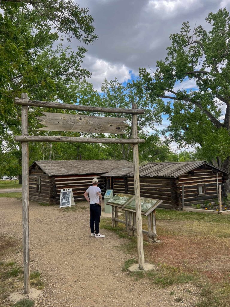 Justin with his back to the camera looking at an old log cabin.