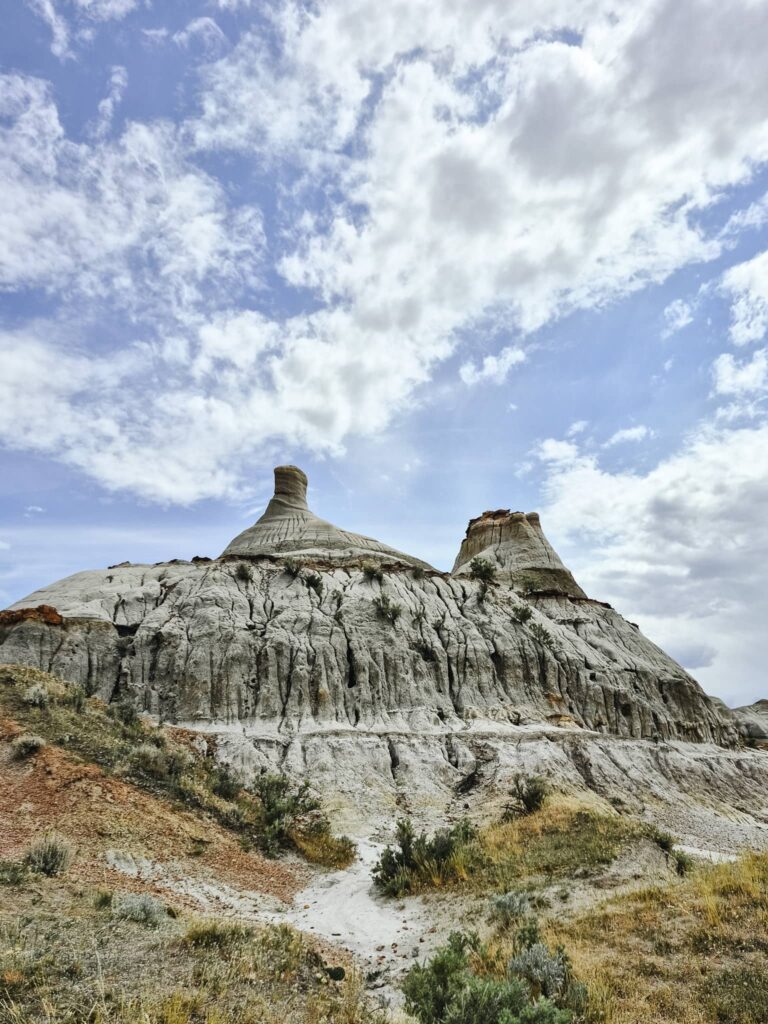 Two eroded hoodoos above a small hill.