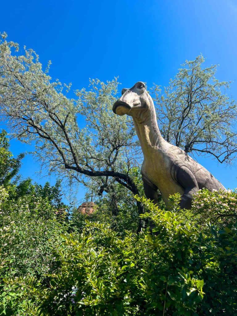 A Hadrosaur statue at the Calgary Zoo looming over the trees.