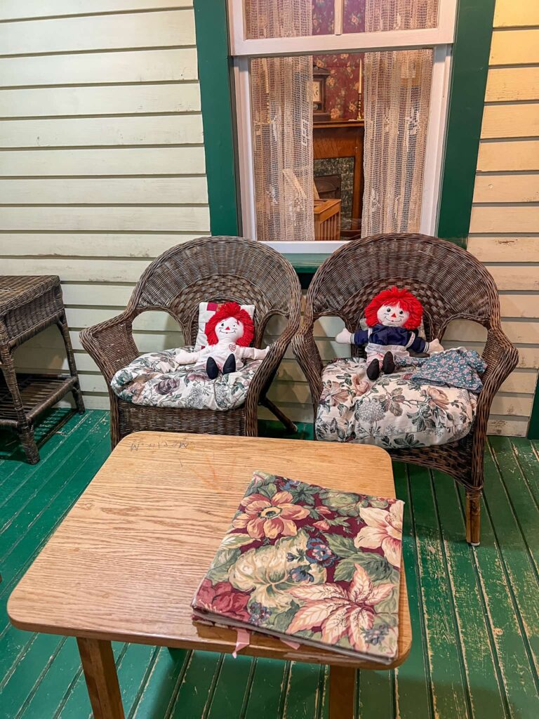 2 Raggedy Ann dolls sit on some woven chairs in the Confluence
