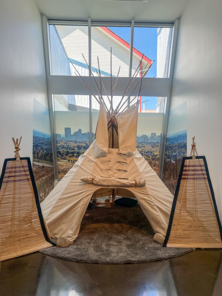 A tipi at the Confluence. It is a cone-shaped tent with canvas covering it. You can see long sticks poking out the top.