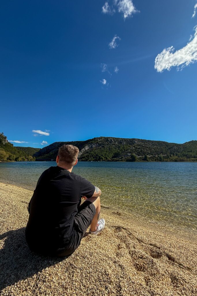 Justin sitting at City Beach of Skradin overlooking the Krka River