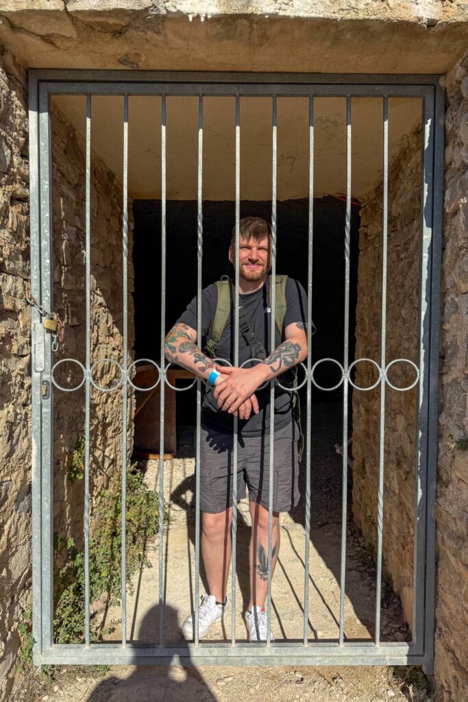 Justin behind a metal gate at the Turina Fortress in Skradin, Croatia