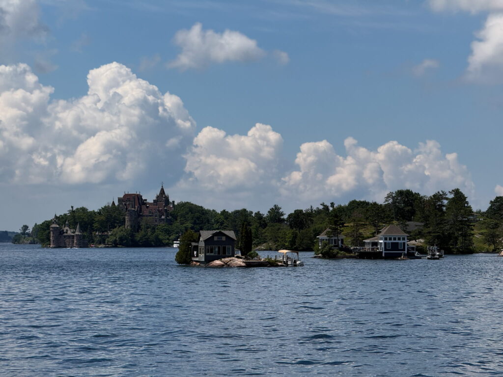 Some cottages and islands of the 1000 Islands. Boldt Castle on Heart Islands is seen in the background.