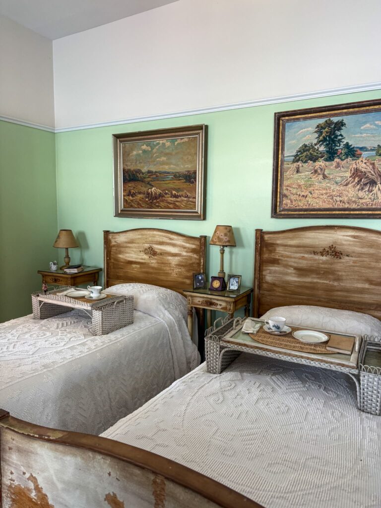 A bedroom in singer castle. There are two twin beds with breakfast trays staged on them.