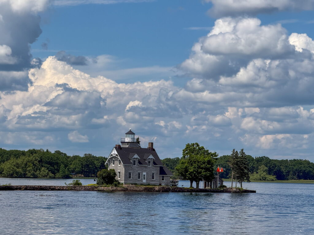 Sisters Island Lighthouse, the top of the lighthouse peeks out from a gray stone house.